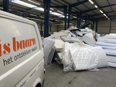 Bedrijfsbus van Jan Buis Baarn bij een stapel matrassen op de recyclinglocatie