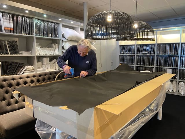 Jan Buis aan het werk met stof in de showroom, tussen de stalenboeken