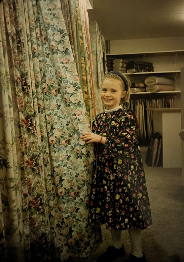 Archieffoto van een kind tussen de gebloemde gordijnstoffen in de winkel