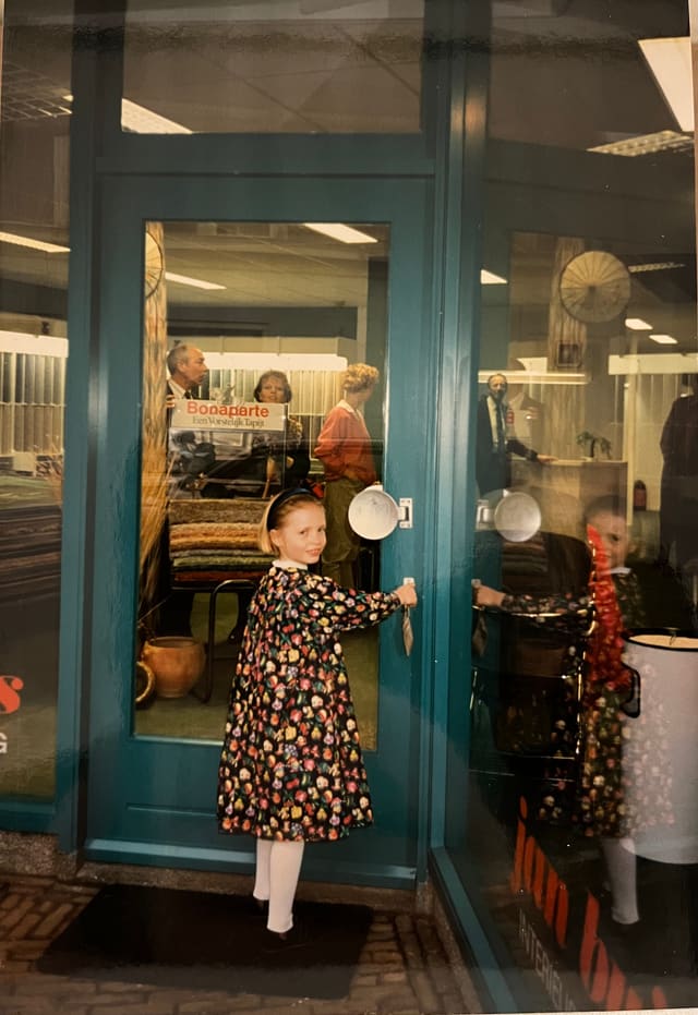 Archieffoto van een kind bij de blauwe voordeur van de winkel